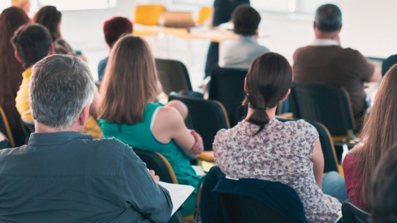 Des adultes de dos participant à une assemblée.
