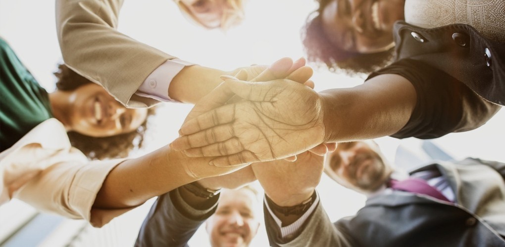 Vue en contre-plongée de collègues d'origines diverses qui joignent leurs mains.