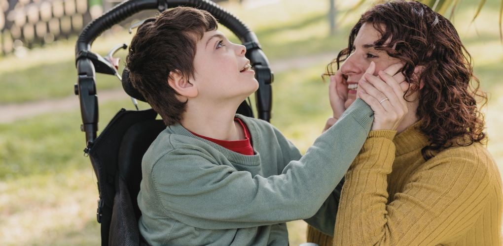 Un enfant handicapé pose les mains sur le visage de sa mère.