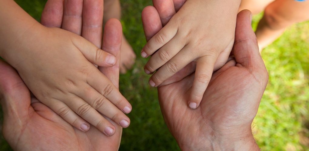 Les mains d'un enfant posées sur celles d'un adulte.